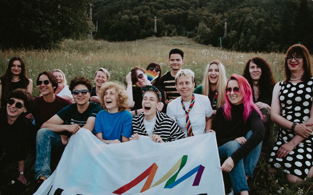 A group of people gathered in the field, smiling and laughing, carrying a banner saying "Insight" in Ukrainian